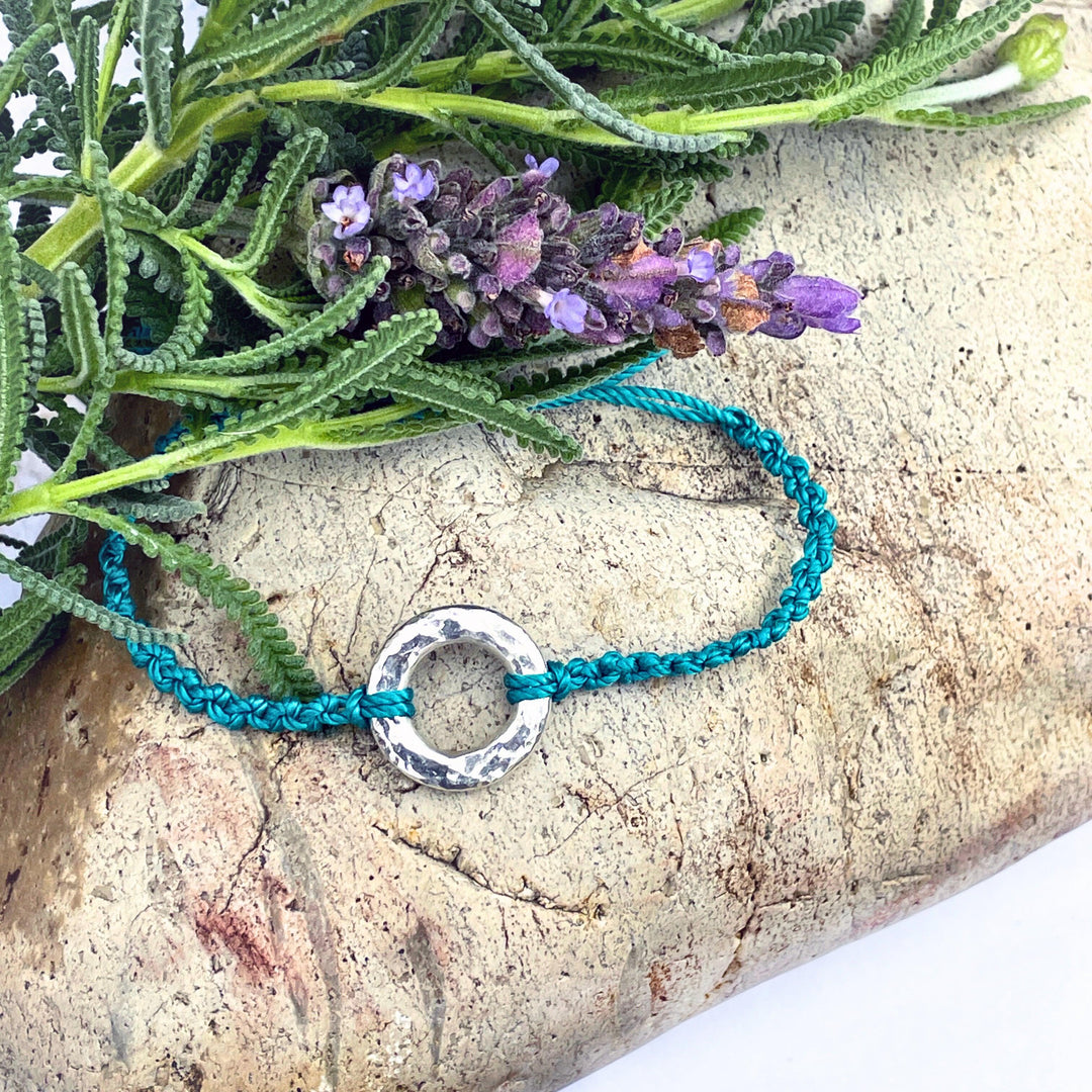 Cremation bracelet with circular silver pendant and nylon teal knotted bracelet