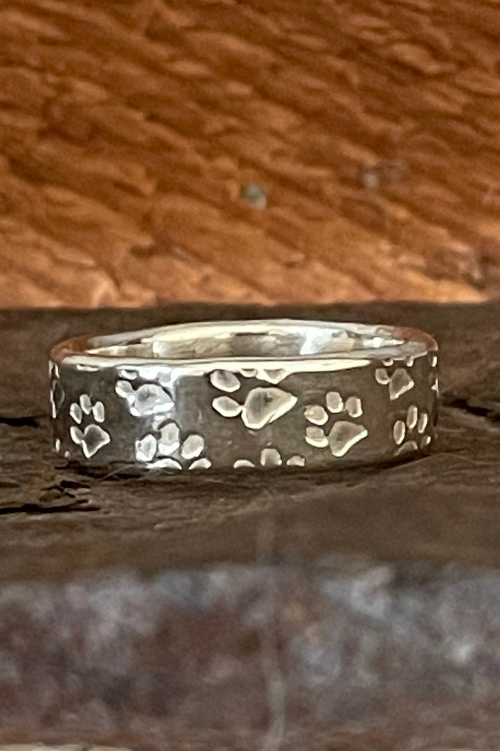 The paw prints are embossed on the sterling silver ring.  The cremation ash is sealed in the core of the ring.