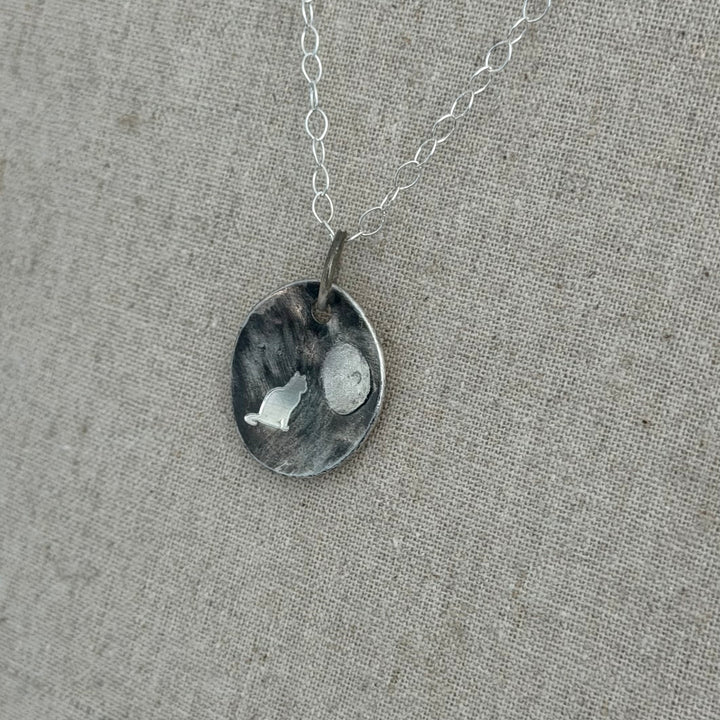 cremation pendant with ashes secure under the moon.   Deep cat engraving on patina darkened background.  solid sterling silver